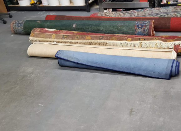 A bunch of area rugs rolled up and ready to be cleaned.